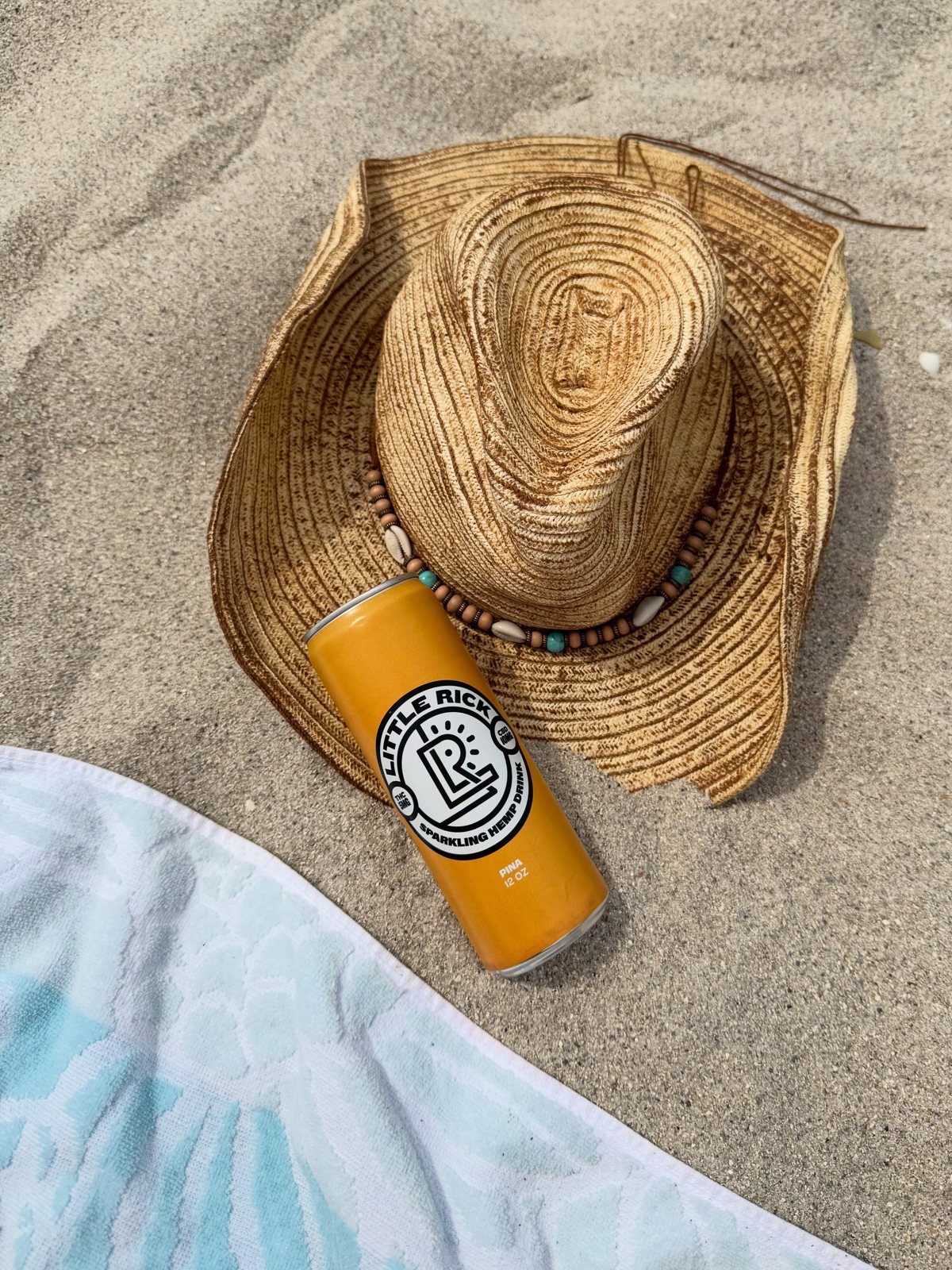 A can of Little Rick Piña on the beach